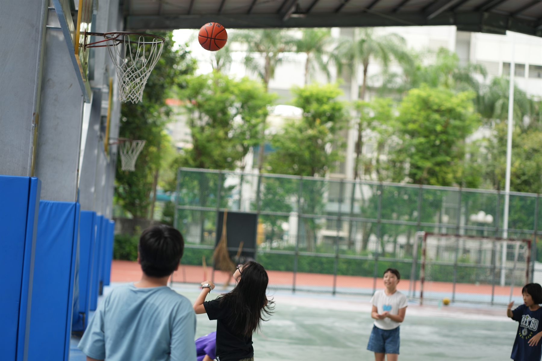 Children playing basketball on a covered court