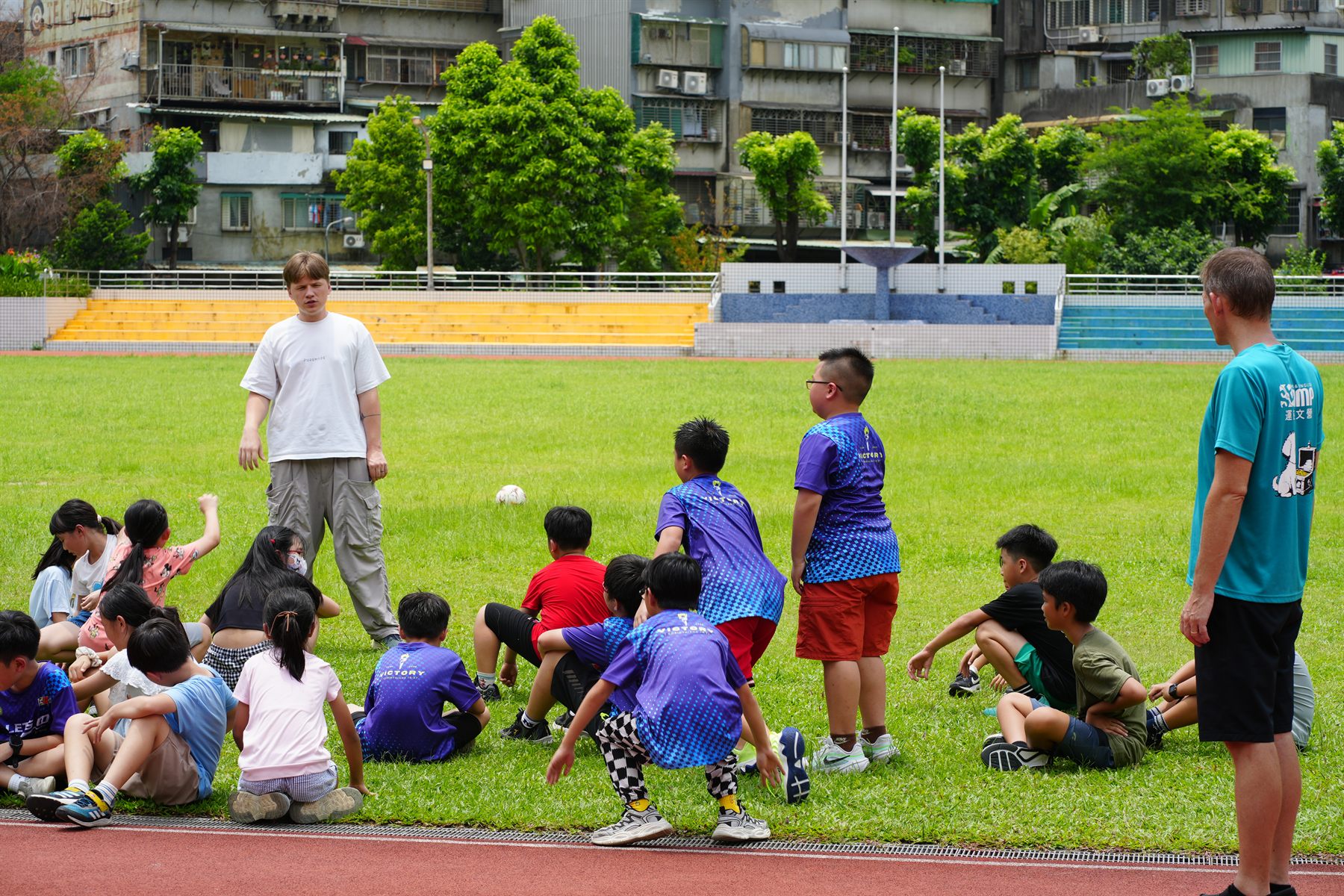 Team leaders and children gathered on a school field in Taipei